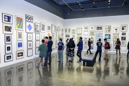 Students in gallery filled floor to ceiling with artworks.