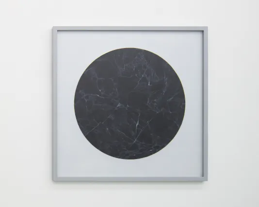 Gray square frame surrounds painting of a circle of black veined marble outlined with gold leaf on paper.