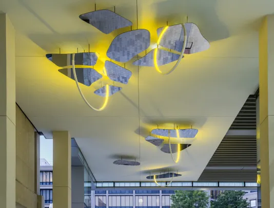 A ceiling bound sculpture of mirror and yellow lights by Olafur Eliasson is installed.