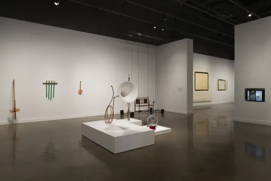 Whimsical musical instruments, as well as a bench surrounded by hanging wires and 4 speakers, and wall-mounted objects.