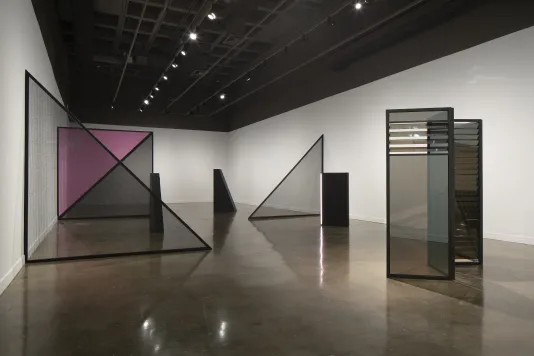 Geometric forms bisect the Gallery, including mirrored rectangles, black and pink triangles and light towers in the same shapes.