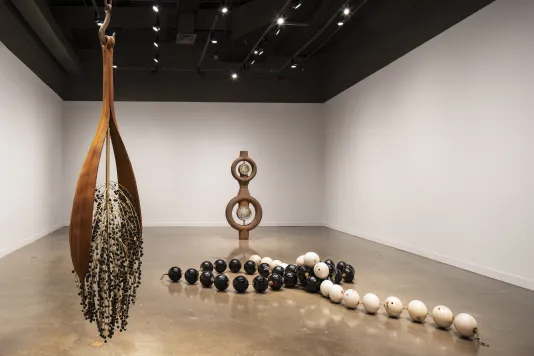 Three large artworks, including metal strips and onyx beads hung from the ceiling, linked bowling balls and a ship’s boiler.