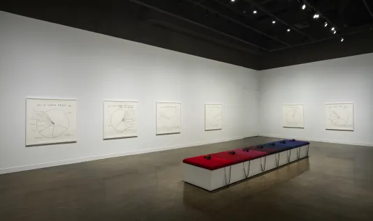 7 cushions ranging from reds to blues to purple with 7 headphones sit atop a white bench surrounded by 6 pie-chart drawings.