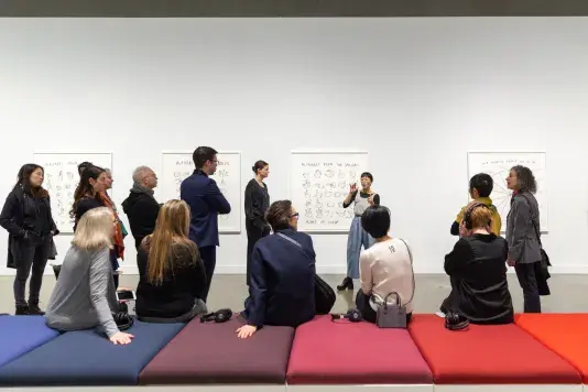 A group of visitors attend a gallery talk with Christine Sun Kim.