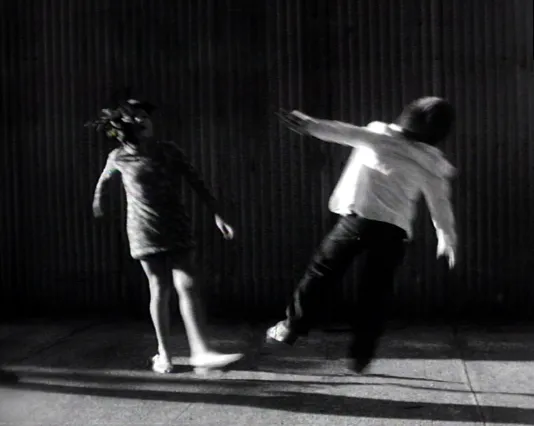 Two children, both with backs to camera, appearing to fall away from one another in a V shape.