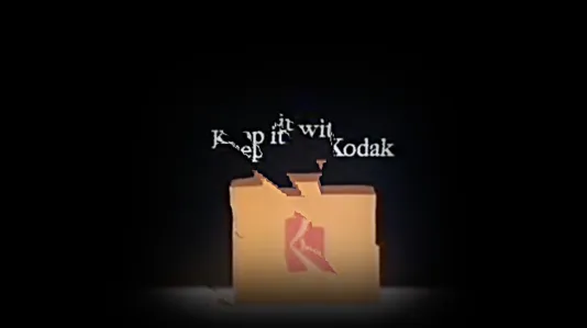 An box of Kodak film with a horizontal glitch, fracturing the Kodak logo. Above, a fragmented slogan reads “Keep it with Kodak”.