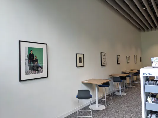 Desks at the Hayden Memorial Library line a wall, displaying four framed works from the Campus Loan Program.