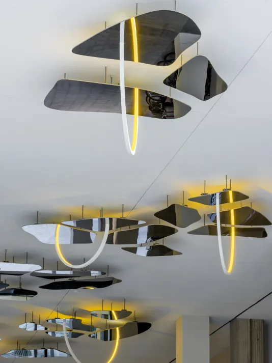 A ceiliing bound sculpture of mirror and yellow lights by Olafur Eliasson is installed.