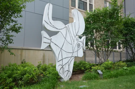 Concrete cut-out sculpture representing a bird with head and beak to the right, tail to the left, feet below, and spread wings above