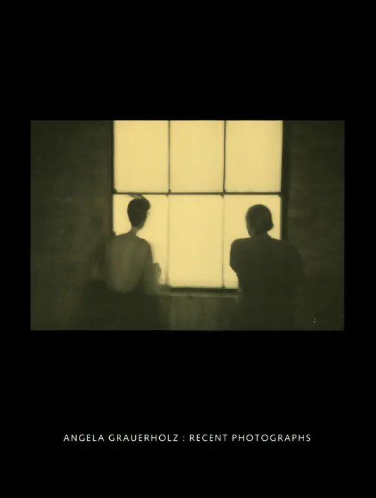 Black book cover for Angela Grauerholz: Recent Photographs featuring a sepia-toned photograph of two people looking out a window.