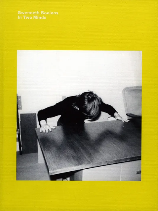 Bright yellow book cover for Gwenneth Boelens In Two Minds featuring a square black and white photograph of a person with both hands on a table leaning over the table.