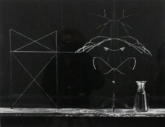 Chalkboard with triangular shapes, an infinity symbol and lines with a shelf below that has a glass pitcher.