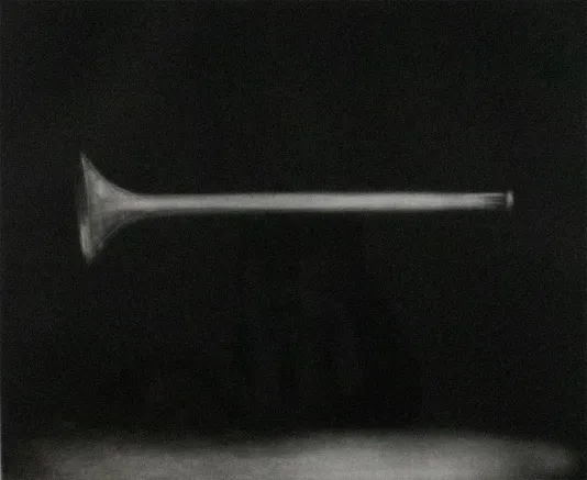 Black background with a grey horn in the center and a light colored shadow on the bottom.