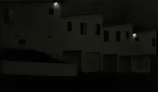 Dark photograph of a building with windows and garages.