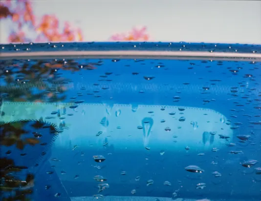 Photograph of a windshield covered in large rain droplets.
