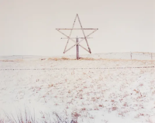 Wooden sculpture of the Star of David photographed on a sand dune.