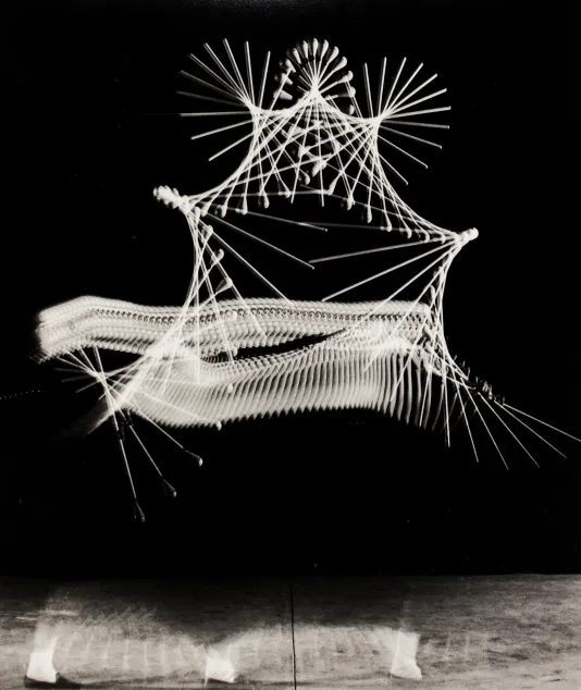 Long exposure photograph of a person swinging batons in the air. The motion of the baton makes shapes out of intersecting lines.
