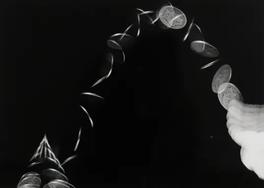 Long exposure photograph of a coin being thrown into the air.