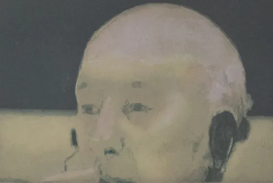 A man's face from the top of his lips up with a bald head and black headphones on.