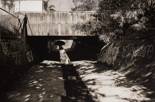 Black and white photograph of a bridge over a stormwater drain.