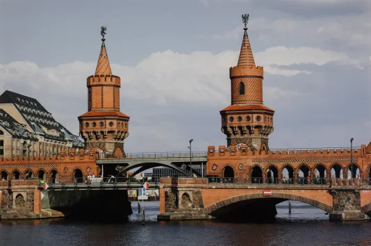 Photograph og a medieval looking bridge over a river with two castle like structures on both sides.