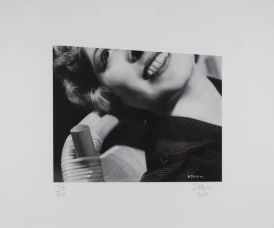 Black and white cut out image of a woman smiling and looking up with the top third of her face cut off.