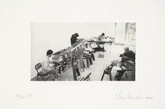 Black and white photograph of people working in a studio on a model bridge.