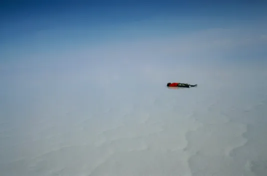Snow covered atmosphere blending in with the sky and a person lying down on the right third.