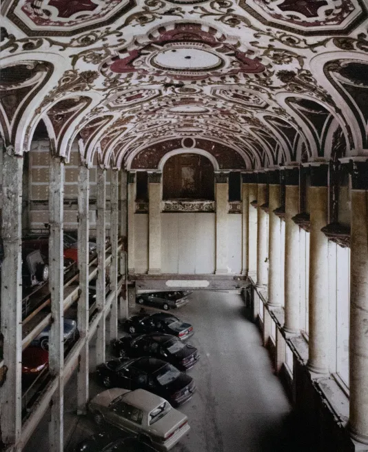 Vertical image of cars parked in an elegant garage featuring a domed ceiling with ornate red and gold decor.