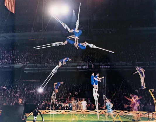 Multiple exposure photograph of a circus where people are ons stilts flipping in the air.