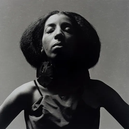 Black and white portrait of Carolee Prince with her eyes closed and her head tilted slightly up.