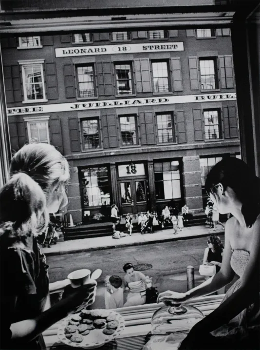 Black and white photograph of two ladies eating at a bakery looking out a large window onto the city street.