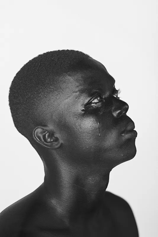 Black and white portrait of a man looking slightly up with a tear streaming down his face.