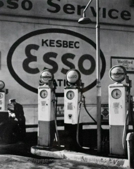 Black and white photograph of three gas pumps and a large sign in the. back that reads "Kesbec Esso"