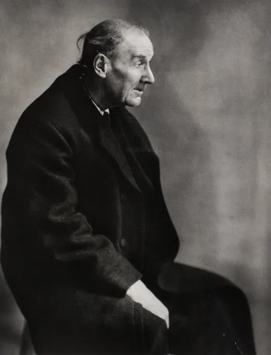 Black and white photograph of an older man from the side sitting in a chair