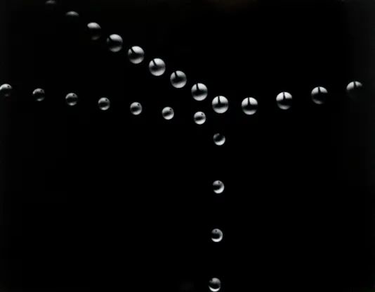 Black background and white and grey circles making an abstract plus symbol across the plane.